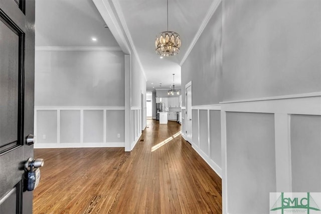 hallway with hardwood / wood-style floors, a chandelier, and ornamental molding