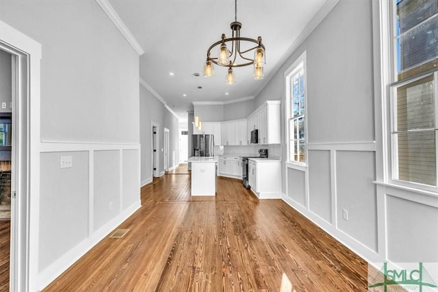 kitchen featuring crown molding, white cabinets, stainless steel appliances, and an inviting chandelier