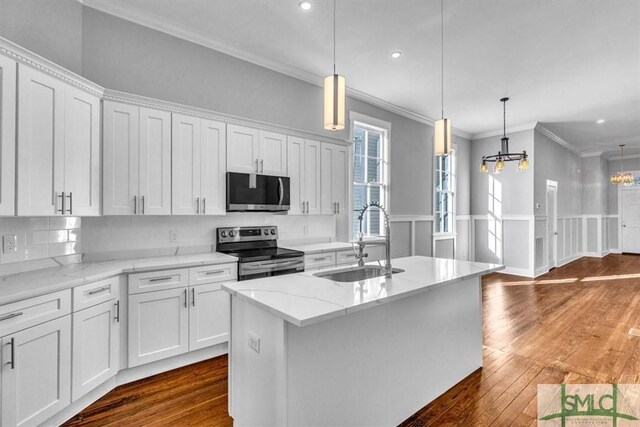 kitchen featuring a center island with sink, sink, appliances with stainless steel finishes, light stone counters, and white cabinetry