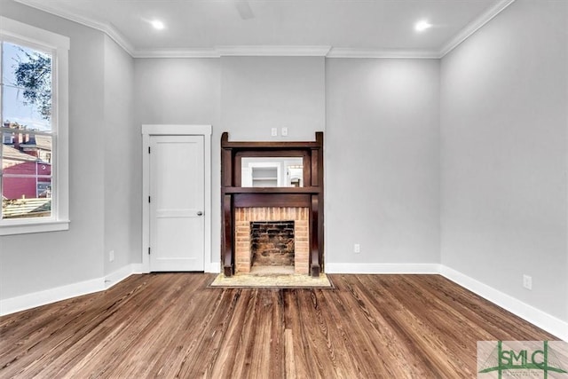 unfurnished living room with a brick fireplace, crown molding, plenty of natural light, and hardwood / wood-style flooring