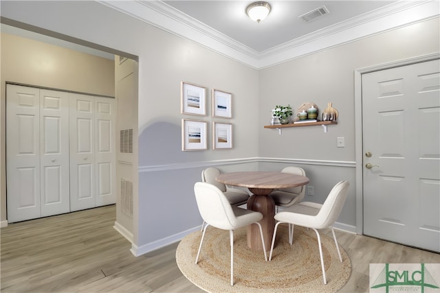 dining area with light hardwood / wood-style floors and crown molding