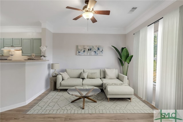 living room with ceiling fan, light wood-type flooring, and crown molding