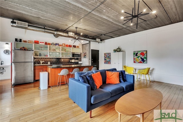 living room featuring an inviting chandelier, light hardwood / wood-style flooring, and sink