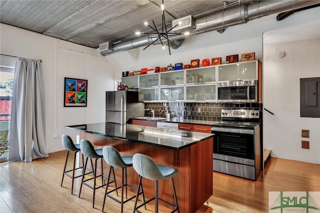 kitchen featuring a kitchen island, stainless steel appliances, backsplash, a breakfast bar, and electric panel