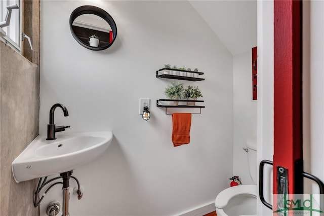 bathroom featuring sink, toilet, and vaulted ceiling