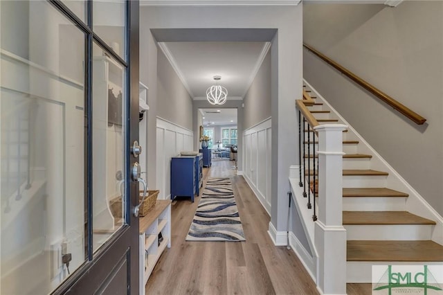 corridor featuring a chandelier, light hardwood / wood-style floors, and ornamental molding