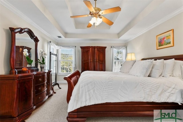 bedroom featuring multiple windows, light carpet, ceiling fan, and a raised ceiling