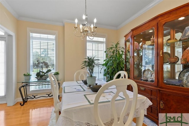 dining space with light hardwood / wood-style flooring, crown molding, and an inviting chandelier