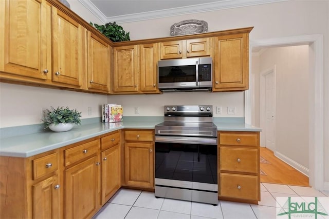 kitchen with light tile patterned floors, stainless steel appliances, and ornamental molding