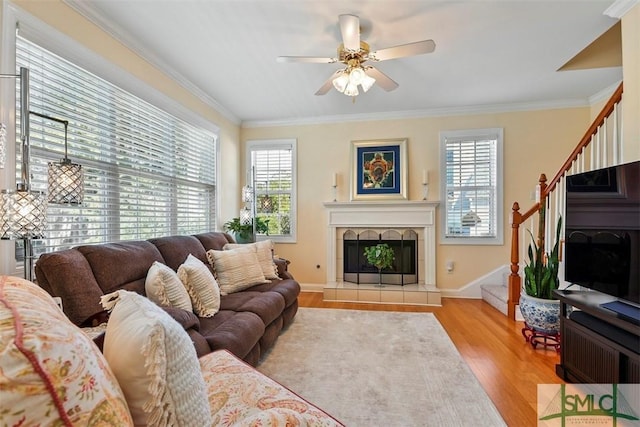 living room featuring a fireplace, crown molding, light wood-type flooring, and ceiling fan