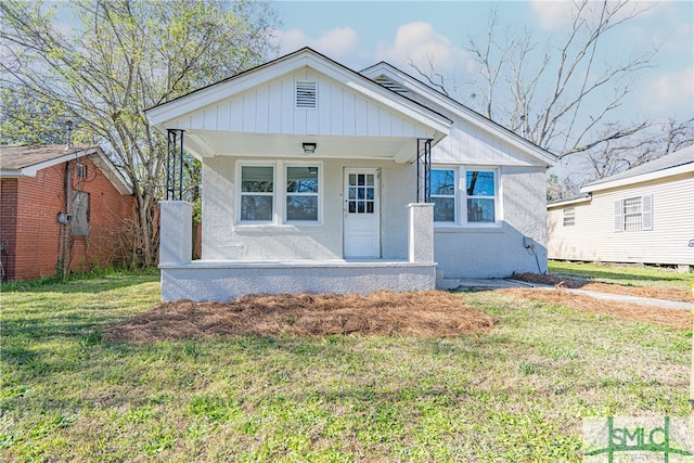 bungalow with a front yard, a porch, stucco siding, and board and batten siding