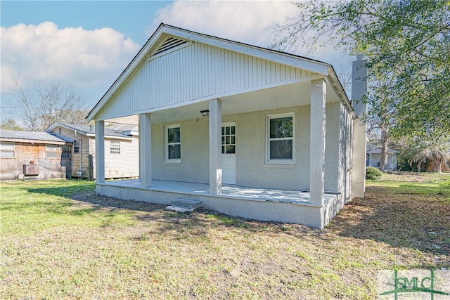 rear view of house with a lawn and covered porch