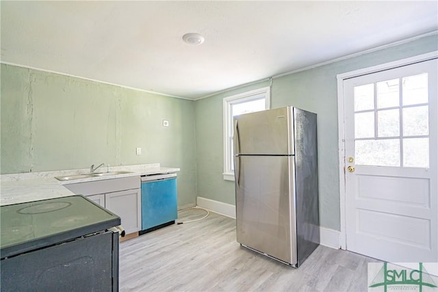 kitchen featuring light wood-type flooring, stainless steel appliances, a healthy amount of sunlight, and sink