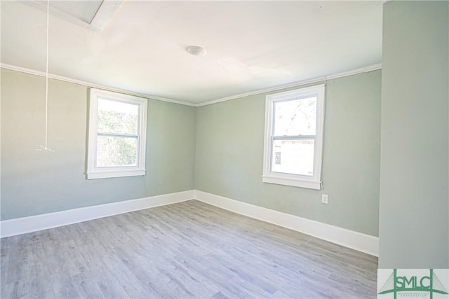 empty room with crown molding, a healthy amount of sunlight, and light hardwood / wood-style floors