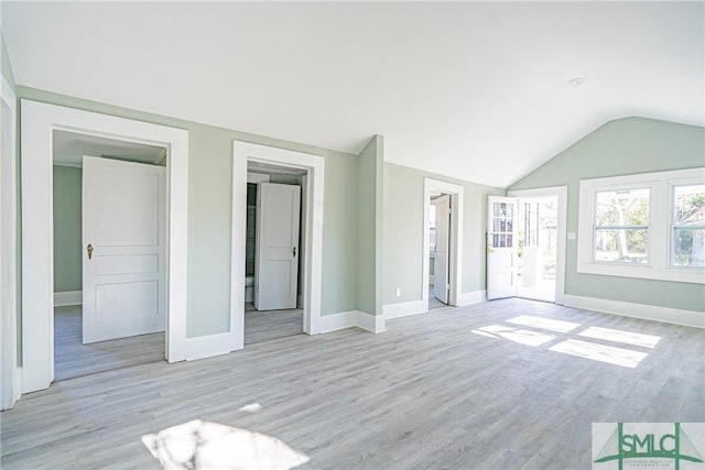 unfurnished bedroom featuring light wood-type flooring, baseboards, and lofted ceiling