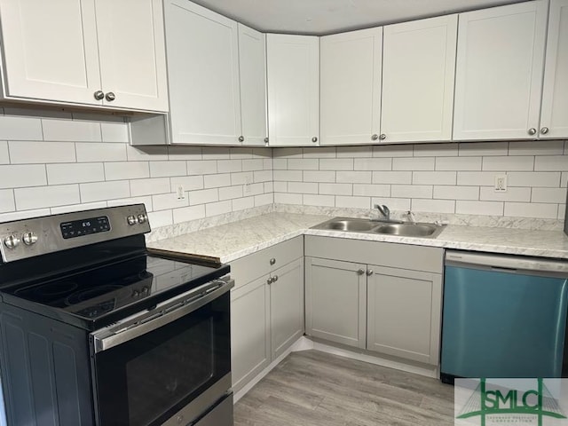 kitchen featuring light wood-style floors, dishwashing machine, stainless steel range with electric stovetop, a sink, and backsplash