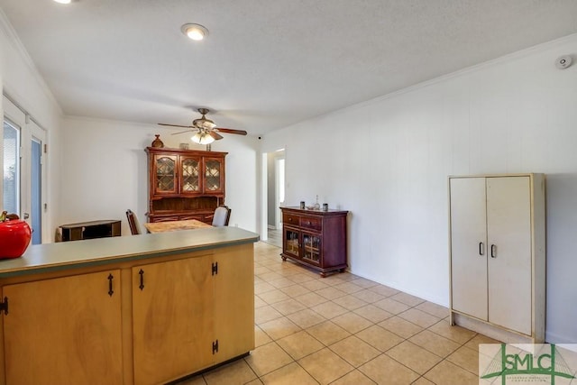 kitchen featuring ceiling fan, crown molding, and light tile patterned flooring