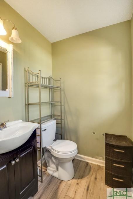 bathroom featuring vanity, wood finished floors, toilet, and baseboards