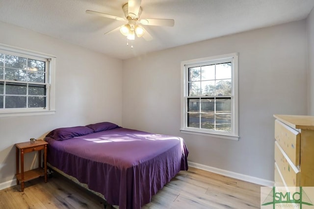 bedroom with a ceiling fan, baseboards, and wood finished floors