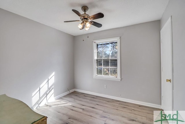 spare room featuring light wood-style floors, baseboards, and a ceiling fan