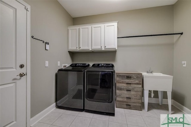 clothes washing area featuring light tile patterned flooring, cabinets, and washing machine and clothes dryer