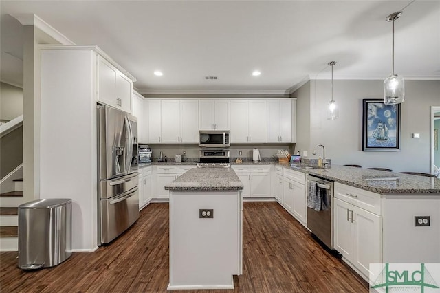 kitchen with kitchen peninsula, appliances with stainless steel finishes, sink, decorative light fixtures, and white cabinetry