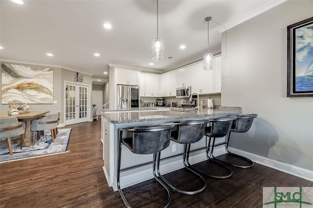 kitchen featuring white cabinets, dark hardwood / wood-style flooring, kitchen peninsula, and stainless steel appliances