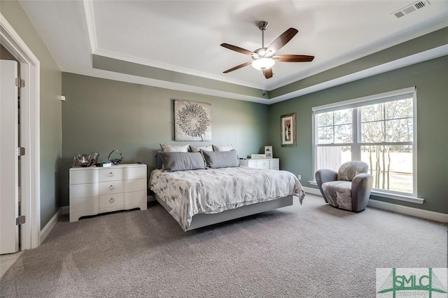 carpeted bedroom featuring a raised ceiling, ceiling fan, and crown molding