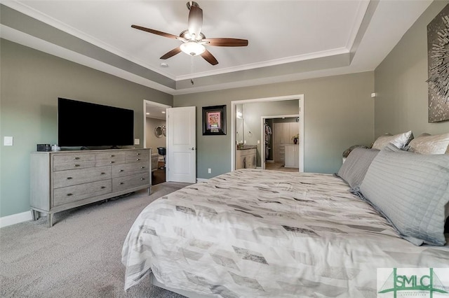 bedroom with a tray ceiling, connected bathroom, ceiling fan, and light carpet