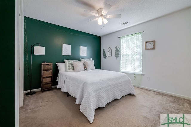 carpeted bedroom featuring ceiling fan and a textured ceiling