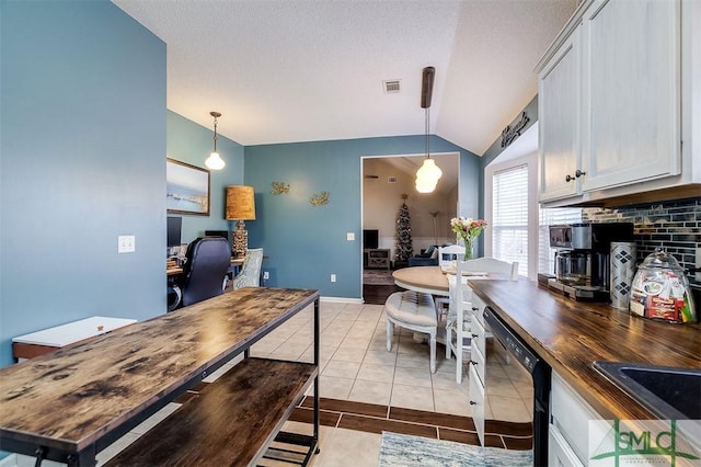 kitchen featuring dishwasher, butcher block countertops, vaulted ceiling, and hanging light fixtures