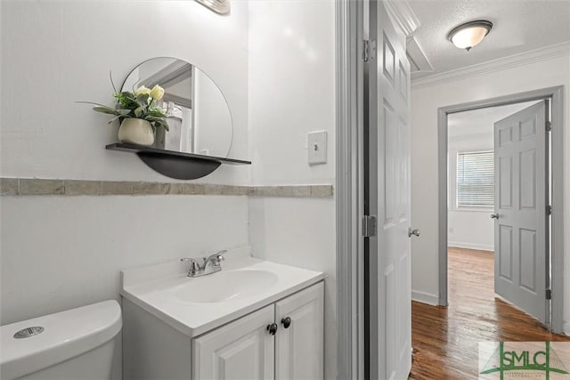 bathroom with crown molding, wood-type flooring, a textured ceiling, toilet, and vanity