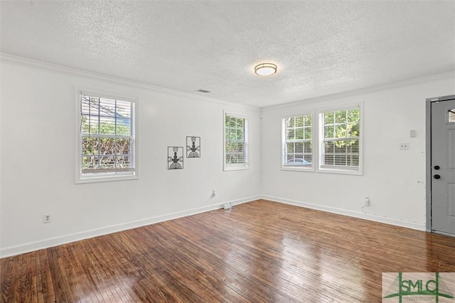 spare room with hardwood / wood-style flooring, a healthy amount of sunlight, ornamental molding, and a textured ceiling