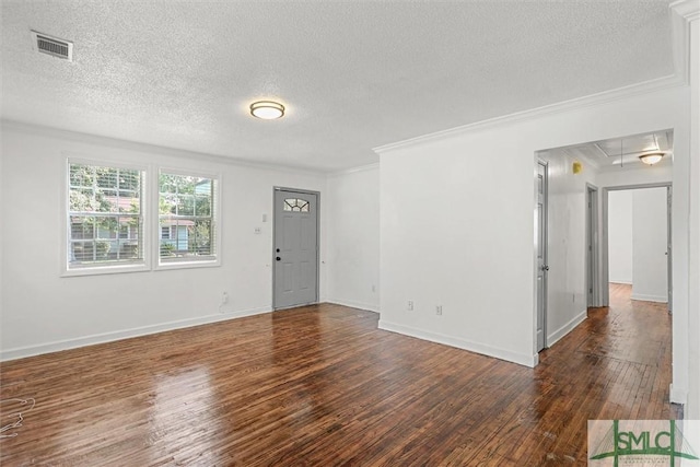 empty room with dark wood-type flooring, a textured ceiling, and ornamental molding