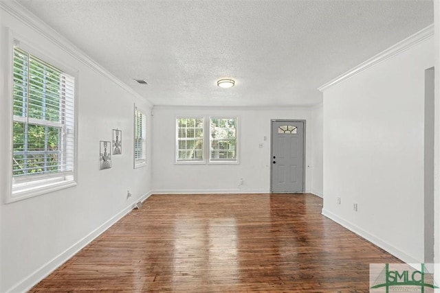 empty room featuring ornamental molding, a healthy amount of sunlight, a textured ceiling, and wood-type flooring