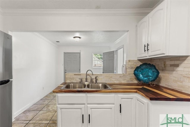 kitchen featuring white cabinets, wooden counters, stainless steel refrigerator, and sink