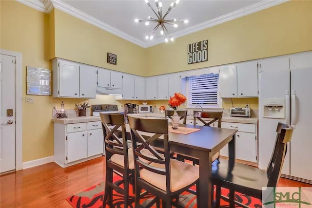 kitchen with a notable chandelier, light hardwood / wood-style floors, white appliances, white cabinets, and ornamental molding