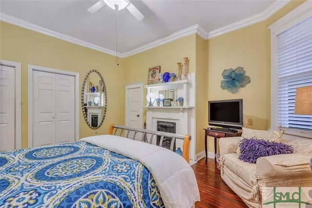 bedroom featuring ceiling fan, a fireplace, crown molding, and dark wood-type flooring