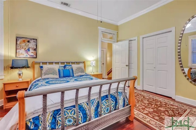 bedroom with hardwood / wood-style floors, two closets, and crown molding