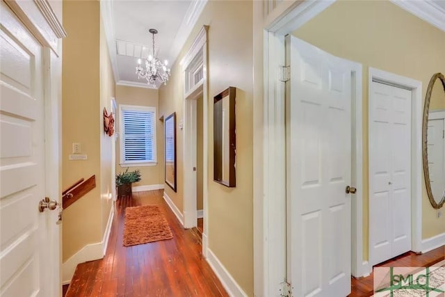 hall with dark hardwood / wood-style floors, ornamental molding, and a notable chandelier