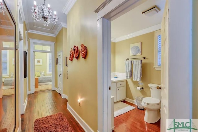 corridor with a chandelier, wood-type flooring, and crown molding