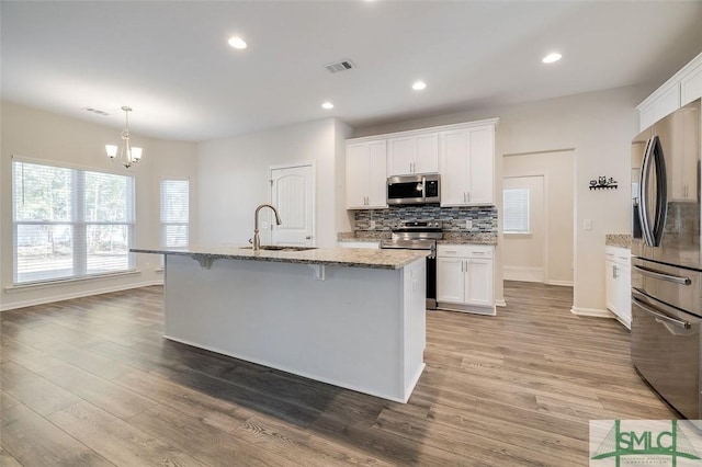 kitchen featuring white cabinetry, sink, stainless steel appliances, and a center island with sink