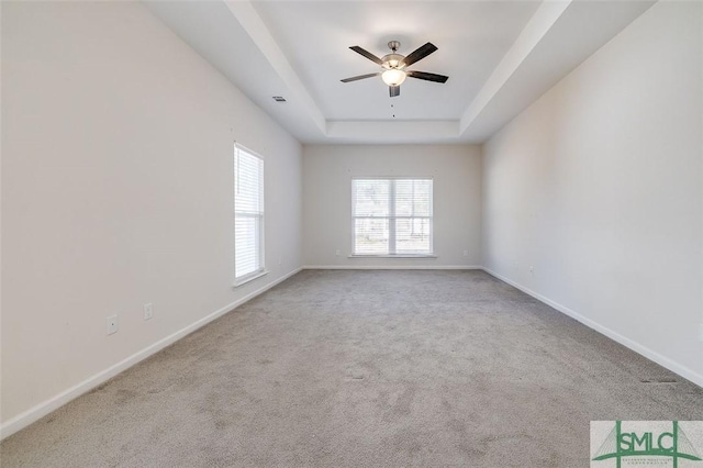 empty room featuring a tray ceiling, ceiling fan, and light colored carpet