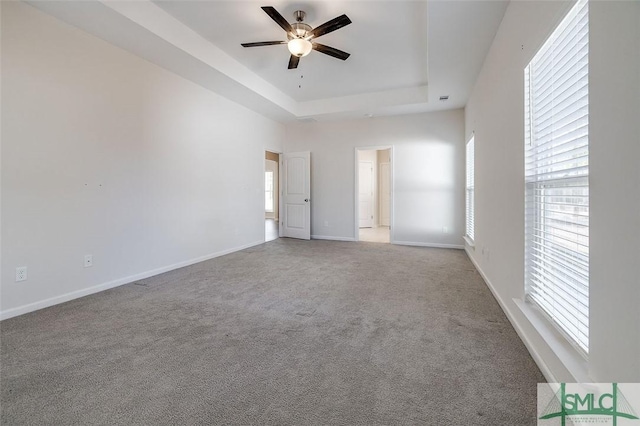 carpeted spare room with a tray ceiling and ceiling fan