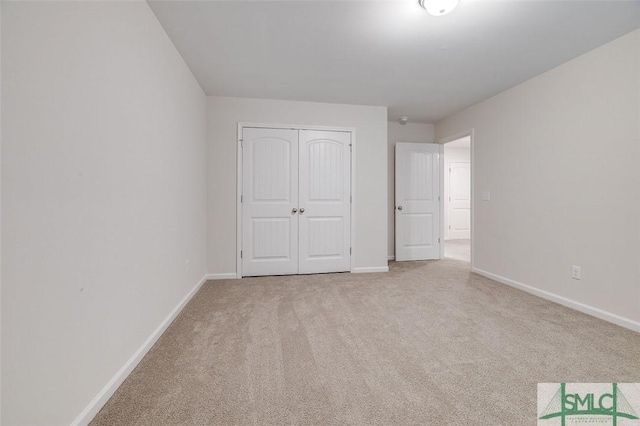 unfurnished bedroom featuring light colored carpet and a closet