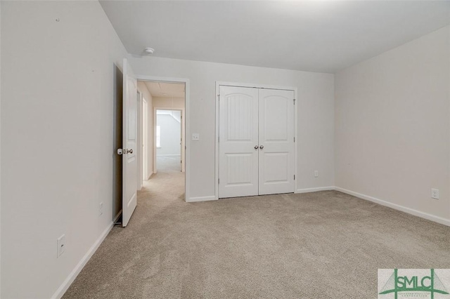 unfurnished bedroom with light colored carpet and a closet