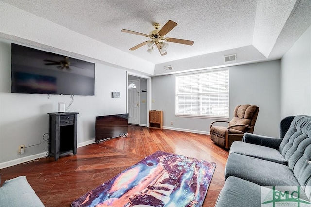 living room with hardwood / wood-style floors, a textured ceiling, a raised ceiling, and ceiling fan