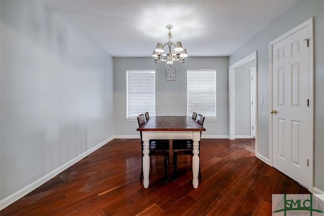 dining room with a textured ceiling, dark hardwood / wood-style floors, and an inviting chandelier