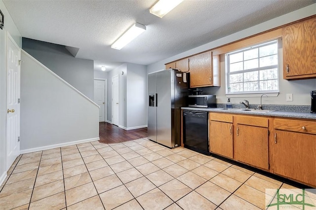 kitchen featuring light tile patterned floors, a textured ceiling, stainless steel appliances, and sink