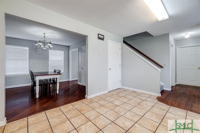 unfurnished dining area with a chandelier, light tile patterned floors, and a textured ceiling